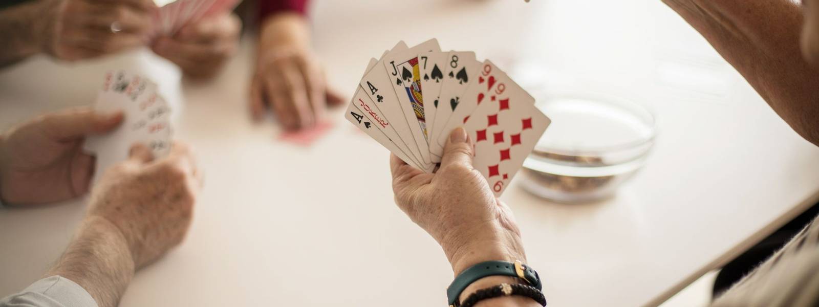 I can do something with this hand. Senior people playing cards at home. Focus is on hands.