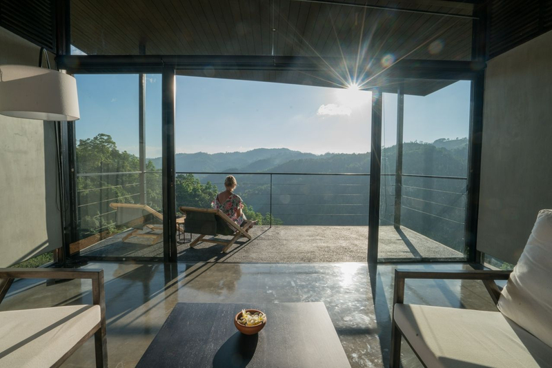 A woman sitting on the terrace overlooking green mountains