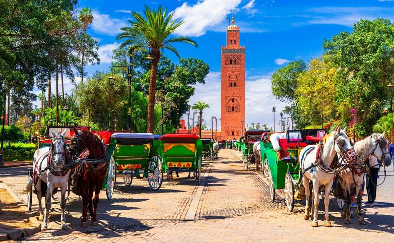 Marrakesh, Morocco: Beautiful view of the horse carriage in front of the Koutoubia Mosque minaret at Medina quarter from Jem…