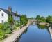 Cottages, bridge and barge  reflecting in the water of  Brecon Canal basin  in Brecon town, Brecon Beacons National Park, Wa…
