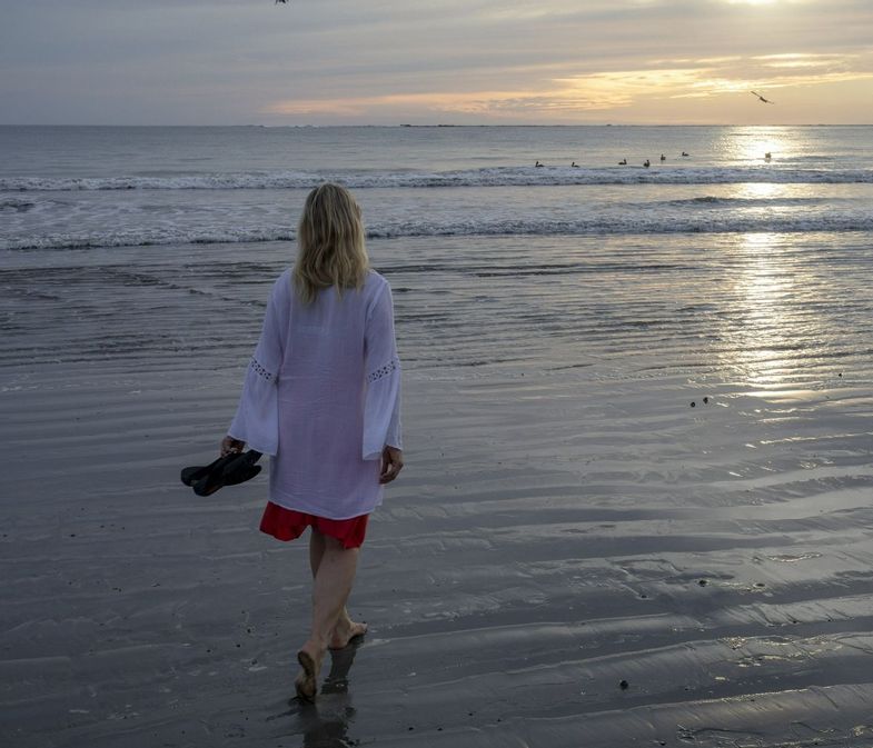 Woman walks along beach at sunrise-Costa Rica-AscentXmedia-iStock