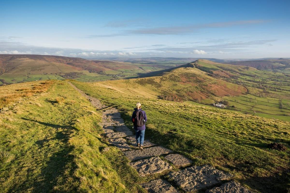 Woman walking the stone path from Mam Tor to Hollins Cross near Castleton in the Peak District, Derbyshire, UK.