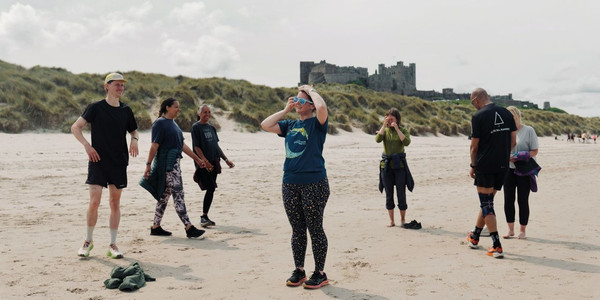 Group photo of 30+ HF Holidays guests, posing for the photo with a large green banner that reads 'HF Holidays: Walk Your Way'