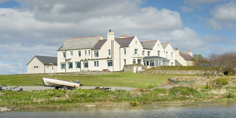 A house on the edge of a serene lake, surrounded by lush greenery and reflecting its beauty in the calm waters.