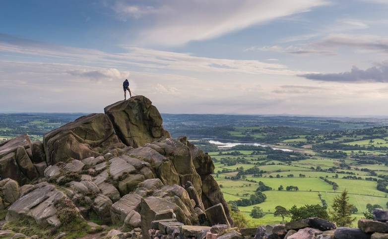 A climber at the roaches with a view over Tittisworth, Peak District National Park