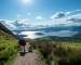 two girls hiking with beautiful lake (loch lomond) and green landscape on a sunny day