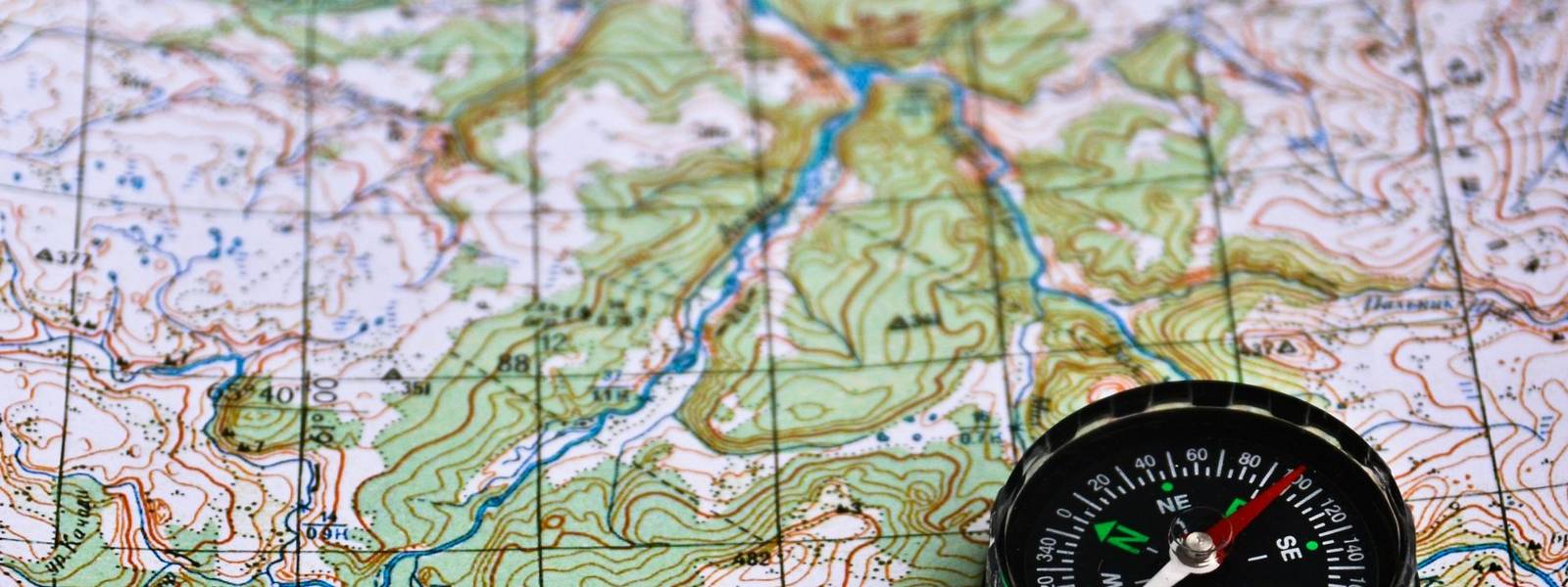 The magnetic compass is located on a topographic map. Satellites adventure - map and compass.