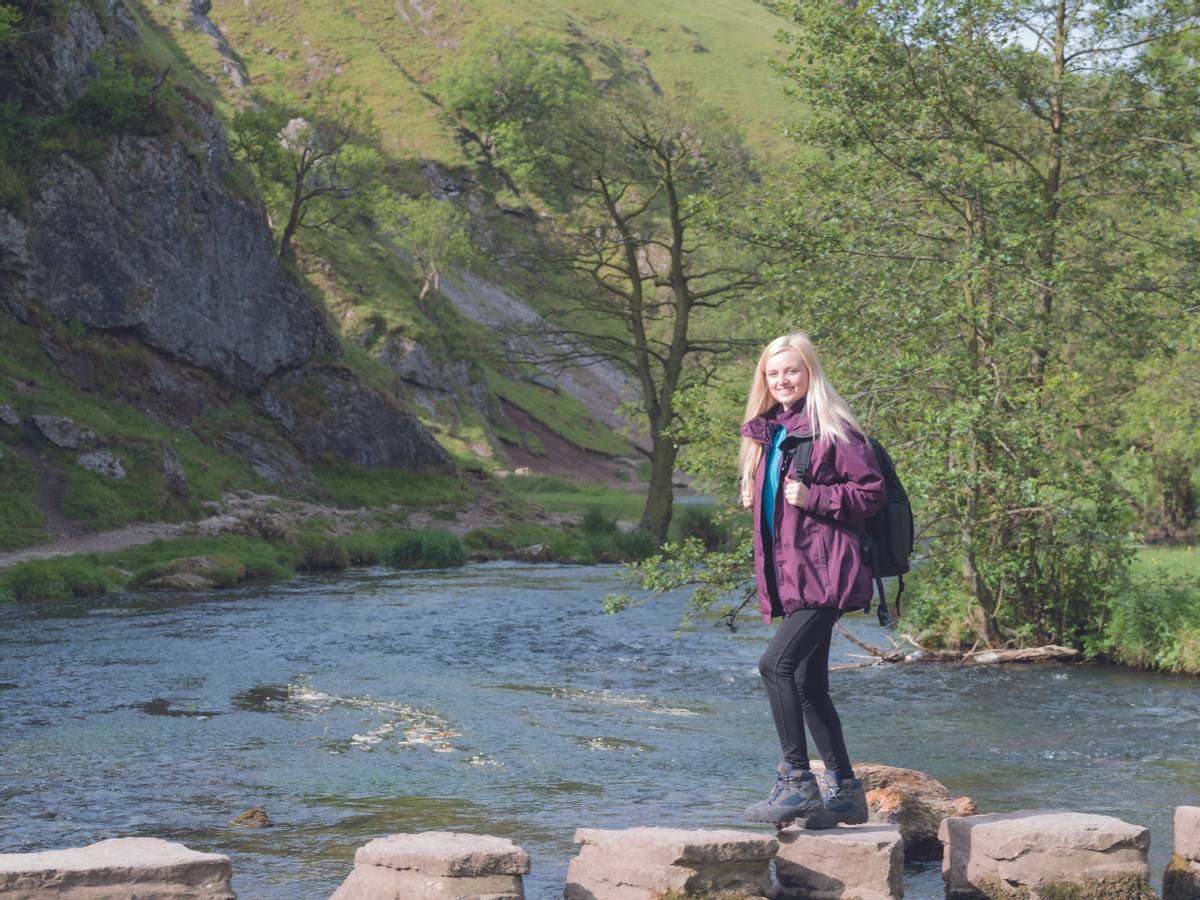 young woman walkin gin dovedale crossing stepping stones