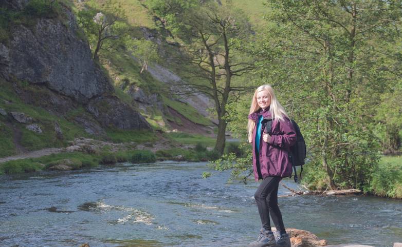 young woman walkin gin dovedale crossing stepping stones
