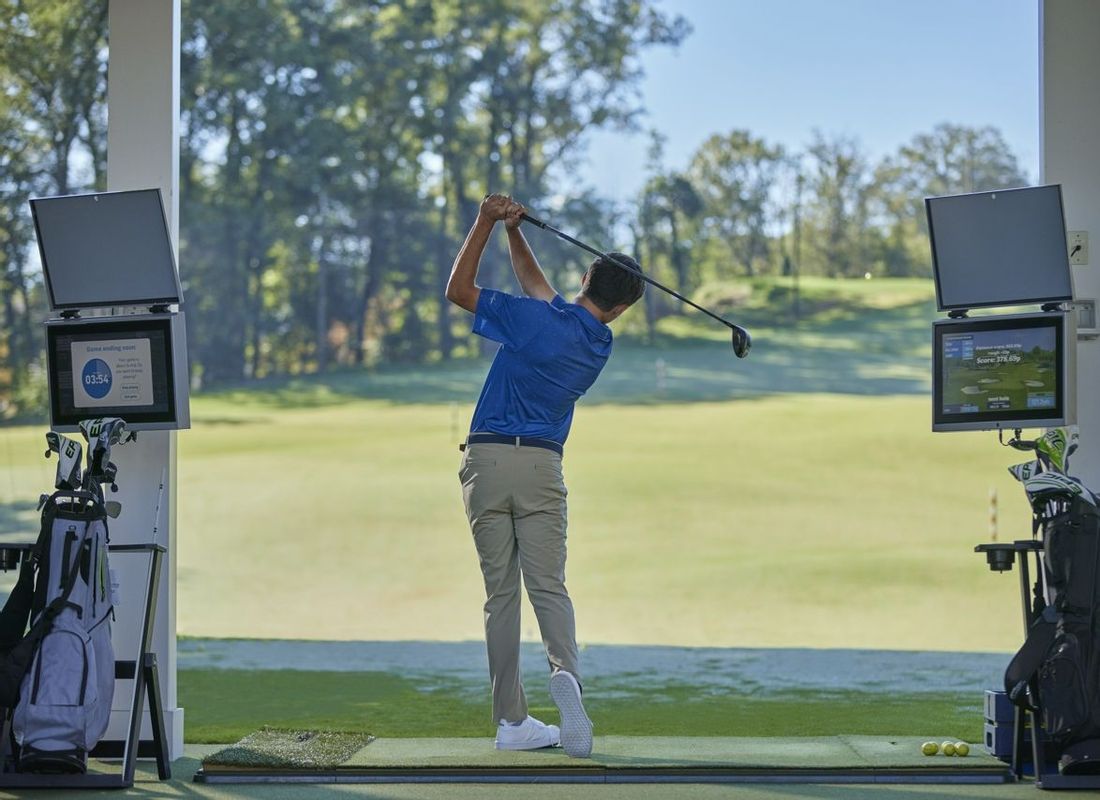 Young man using Toptracer driving range on a sunny day