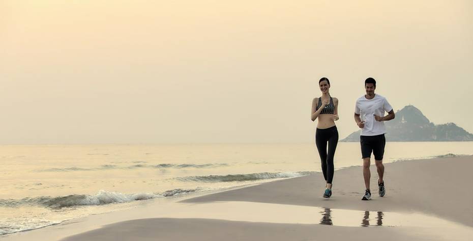 Healthy Couple running on the beach on a winter wellness retreat