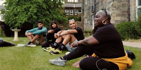 Group of hikers on a nature path, with their arms stretched out towards the sky, posing for the camera. 