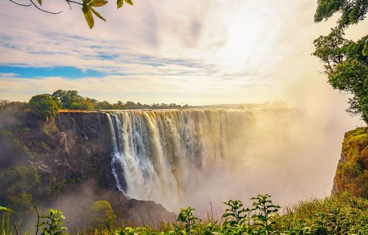 Sunset at the Victoria Falls on Zambezi River located between Zambia and Zimbabwe, the largest waterfall in the world. Sunset at the Victoria Falls on Zambezi River located between Zambia and Zimbabwe, the largest waterfall in the world.