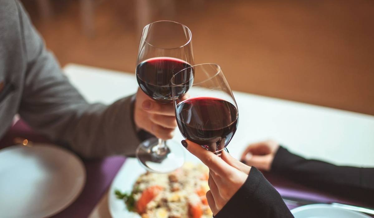 Beautiful young couple with glasses of red wine in luxury restaurant