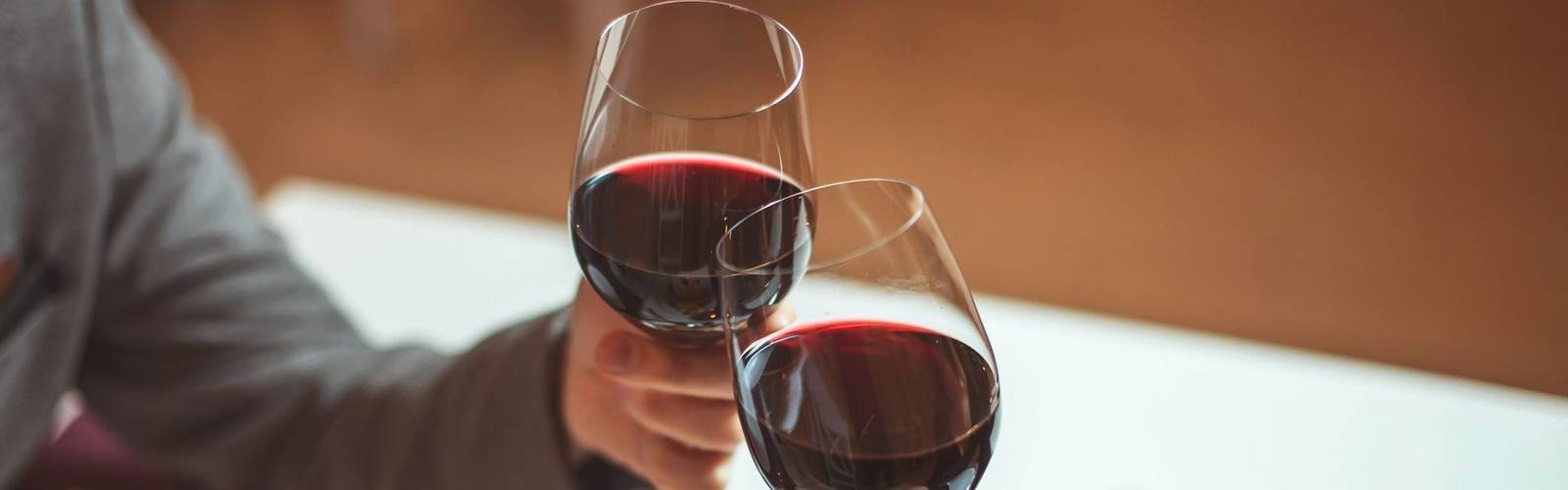 Beautiful young couple with glasses of red wine in luxury restaurant