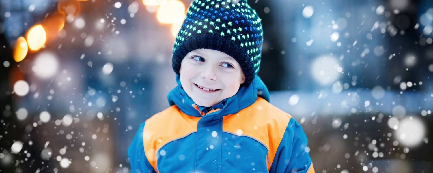 Funny little kid boy in colorful clothes playing outdoors during snowfall Credit Irina Schmid.