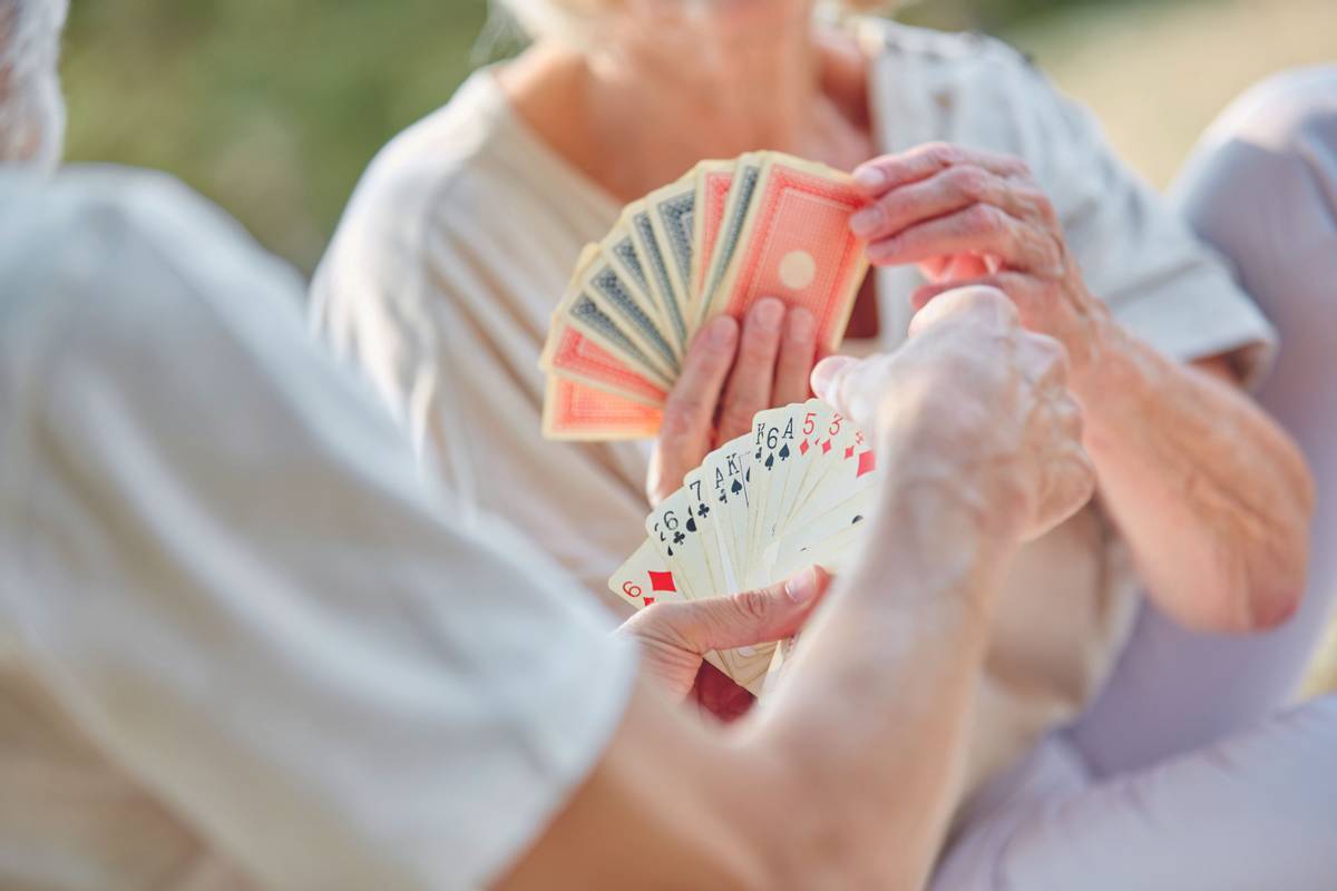 Two retired seniors playing cards as a hobby in the garden in summer