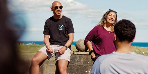 Group of hikers on a nature path, with their arms stretched out towards the sky, posing for the camera. 