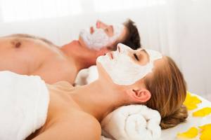 17260977 - man and woman in face masks lying back on clean white towels in a spa relaxing