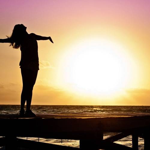 Woman with outstretched arms in the sunset