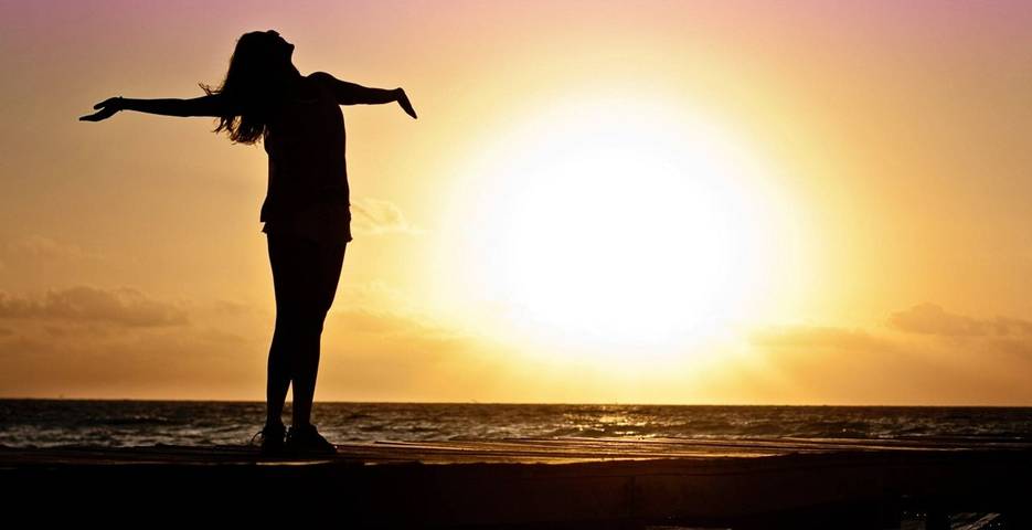 Woman with outstretched arms in the sunset