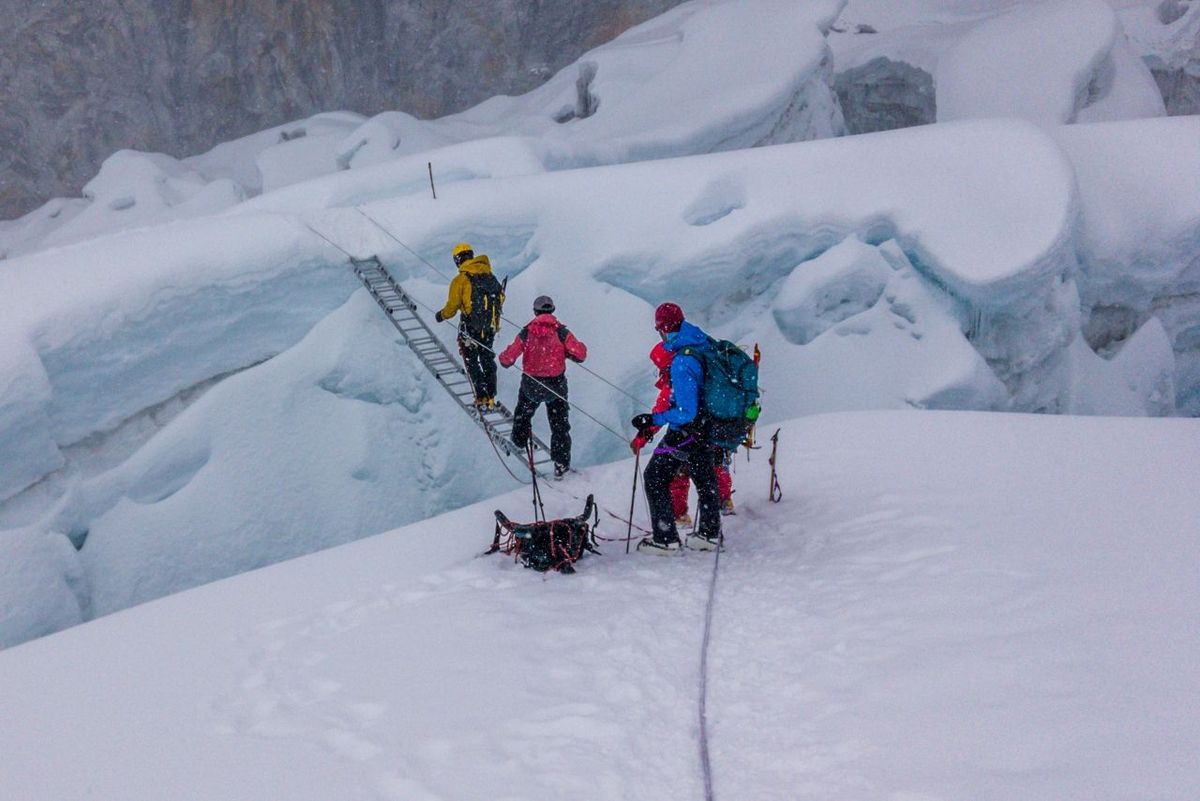 A group of climbers crossing a crevasse over a ladder, Island Peak, Everest Region, Nepal