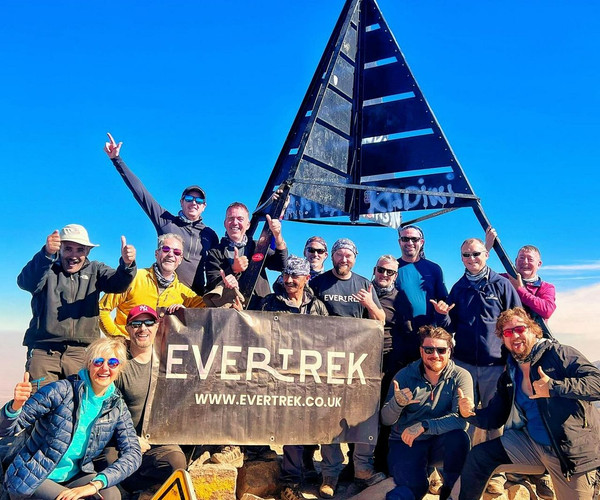 A group of hikers celebrating their success at the summit of Mount Toubkal in Morocco