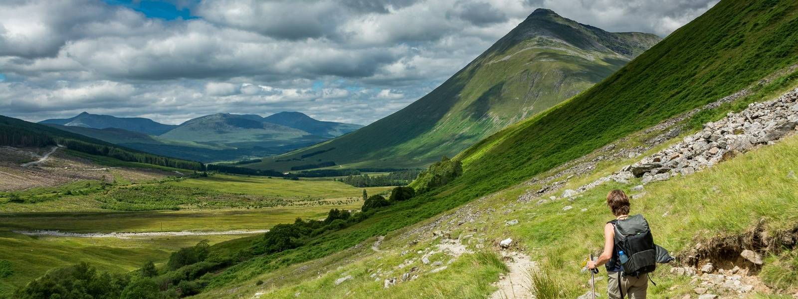 Along the West highland Way in Scotland. A hiker walks on the hiking trail in a hilly landscape dominated by the Beinn Dorain.