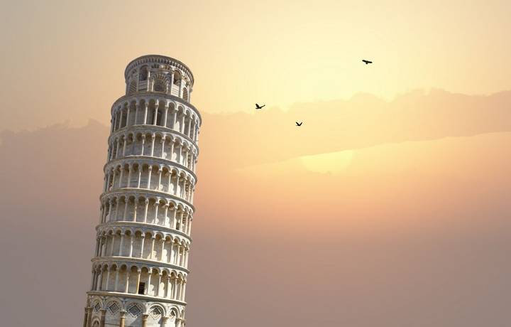 View of historical Pisa Tower in Cathedral Square of Pisa, Italy, on sunrise or sunset sky background.