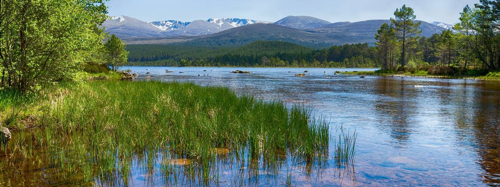 The clear waters of Loch Morlich, Scotland.  The Cairngorm mountains in the background.