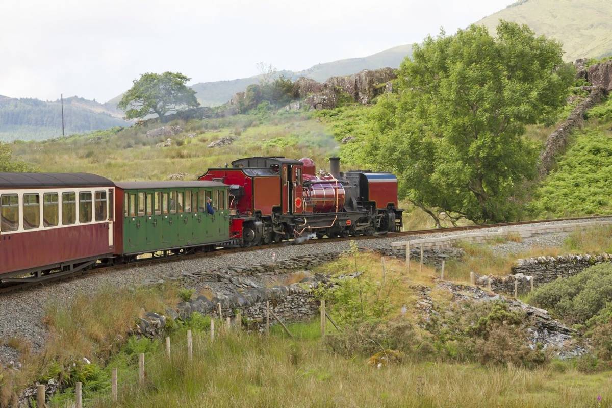 UK - Wales - Red steam locomotive (class garratt) pulls the old heritage train through Wales wilderness on Welsh Highland Ra…