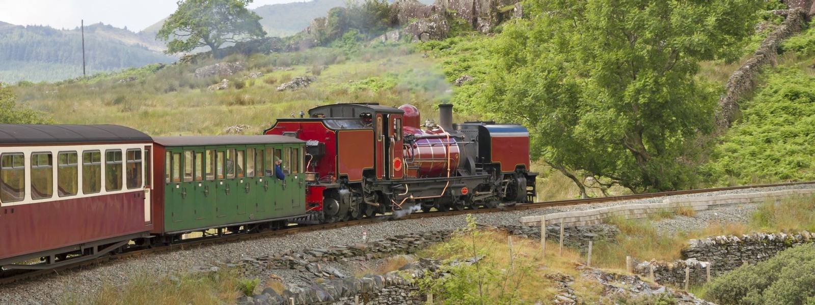UK - Wales - Red steam locomotive (class garratt) pulls the old heritage train through Wales wilderness on Welsh Highland Ra…