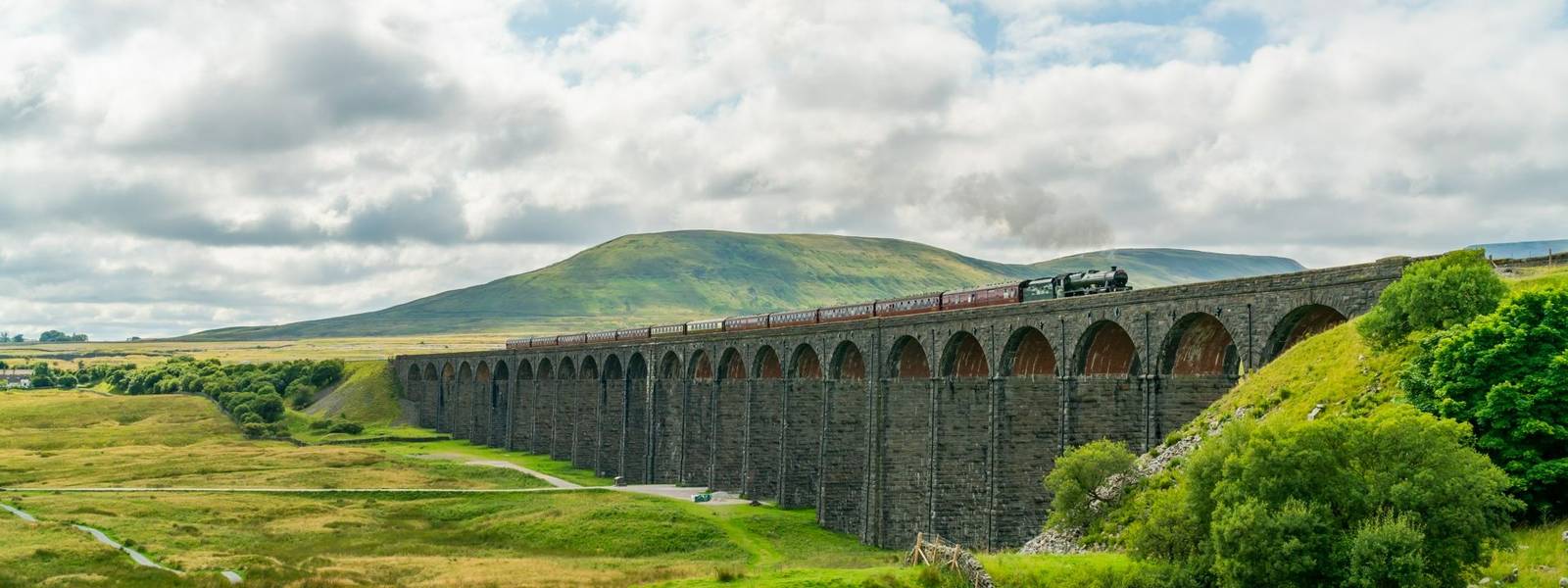 View of Ribblehead Viaduct (or Batty Moss Viaduct) with steam train in Yorkshire Dales, North Yorkshire, UK