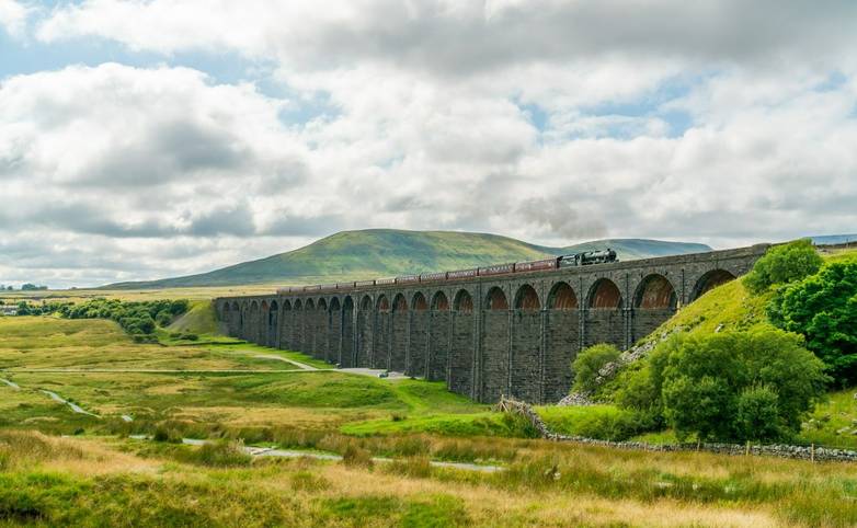 View of Ribblehead Viaduct (or Batty Moss Viaduct) with steam train in Yorkshire Dales, North Yorkshire, UK
