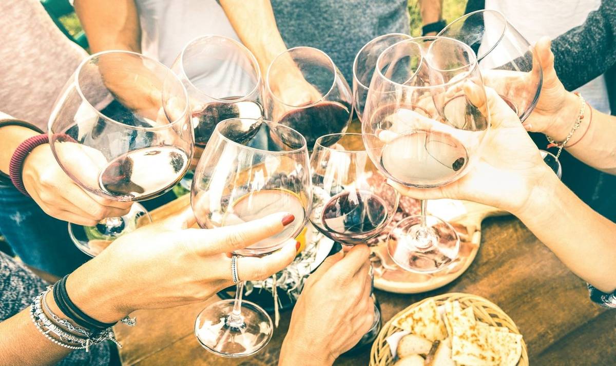 Friend hands toasting red wine while having fun outside cheering with winetasting - Young people enjoying  drinks on harvest…