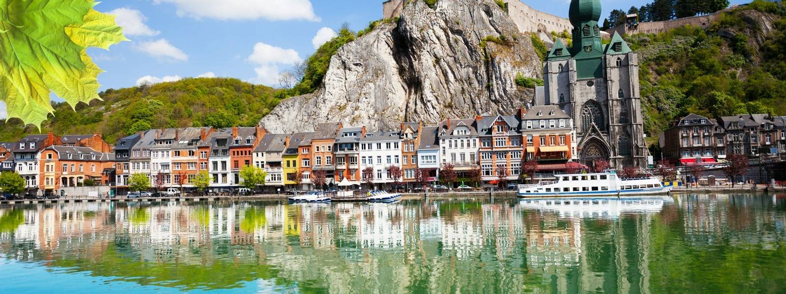 Meuse river with Collegiale Notre Dame, Citadelle de Dinant with white ship in Belgium