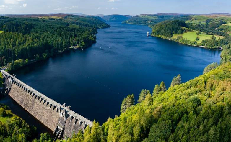 Aerial view of a huge lake surrounded by rural farmland and forest. (Lake Vyrnwy, Wales)