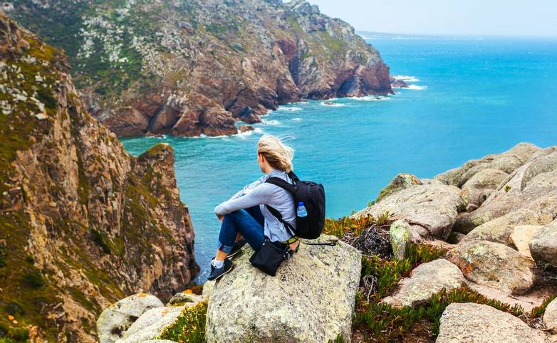 Female tourist sitting on Cape Roca, Sintra, Portugal