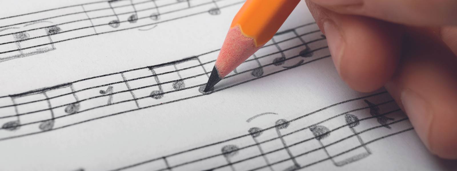 Woman writing music notes on sheet with pencil, closeup