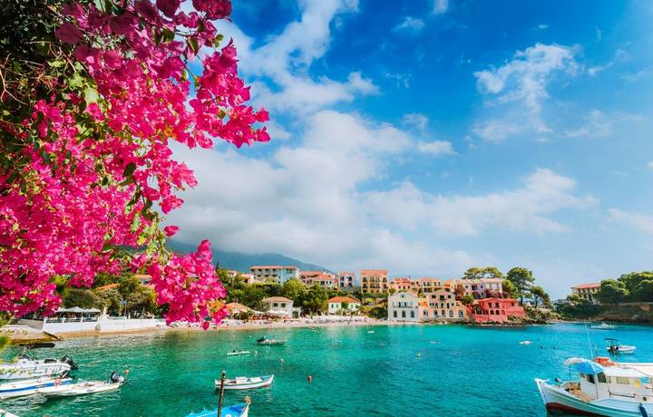 Beautiful Assos village scenery framed with branch of magenta blossom fuchsia flower. Summer vacation concept. Beautiful Assos village scenery framed with branch of magenta blossom fuchsia flower. Summer vacation concept.