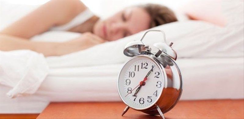 Woman sleeping next to alarm clock.