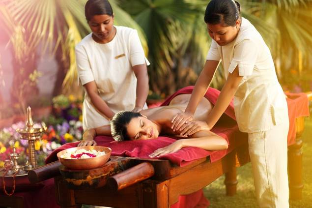 Woman getting floral massage from two therapists.