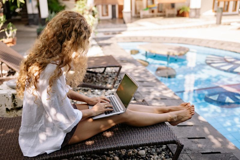 Woman sat with laptop by pool