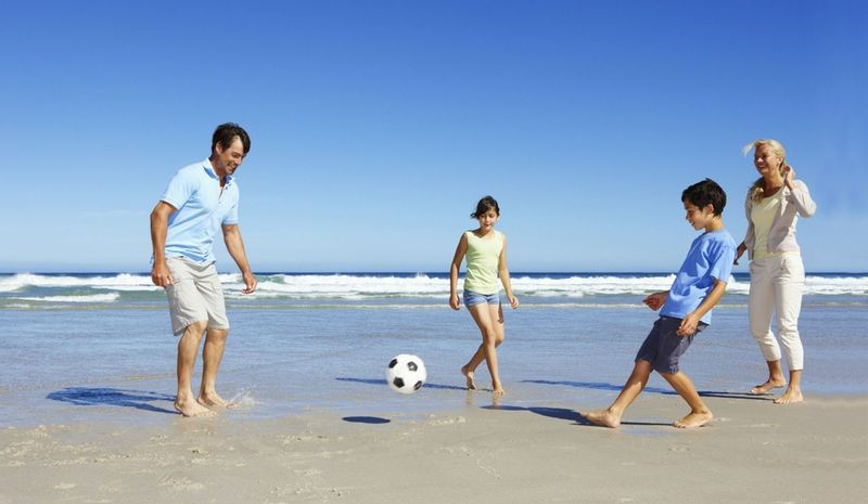 A family playing football on a beach at a holiday retreat